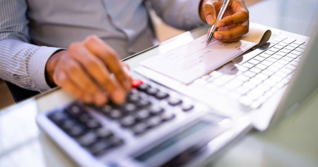 Personne qui tape sur calculatrice et écrit de l'autre main